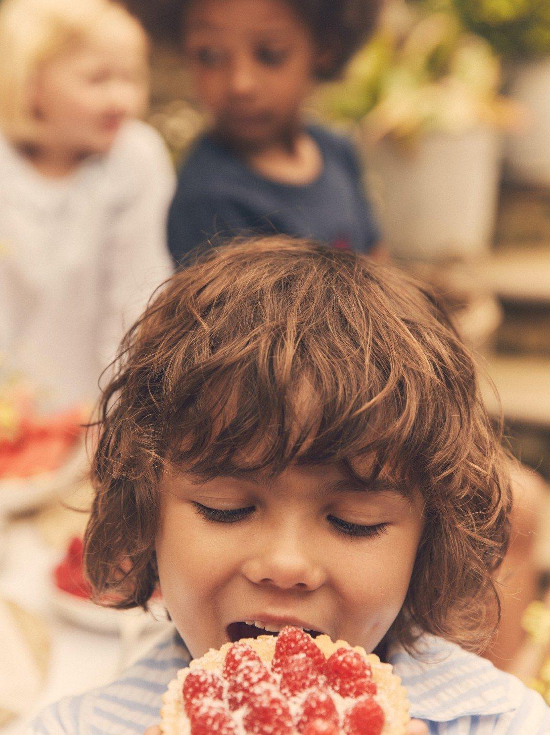 a young boy eating a piece of cake with strawberries on top