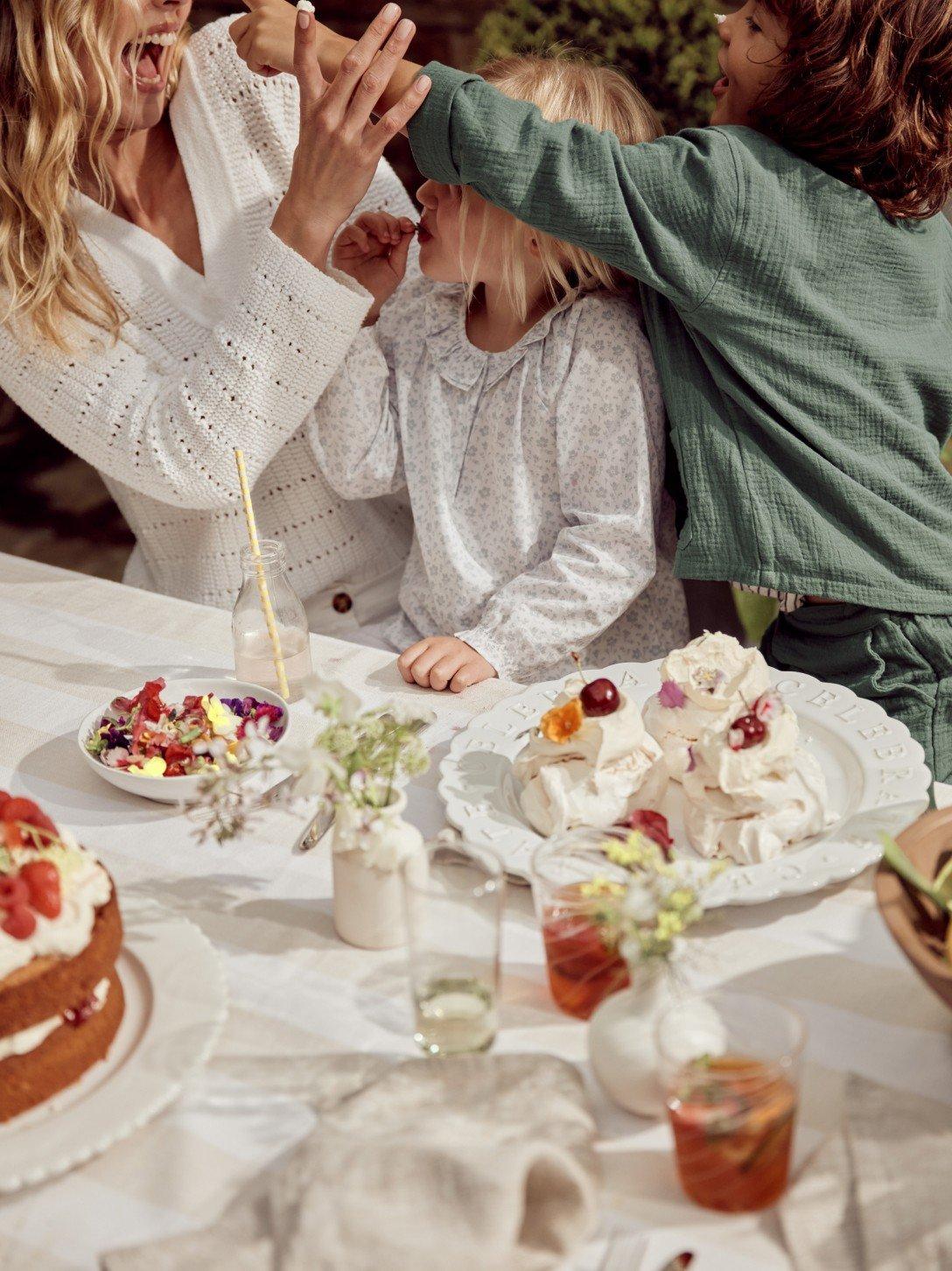 a woman and two children standing at a table with food