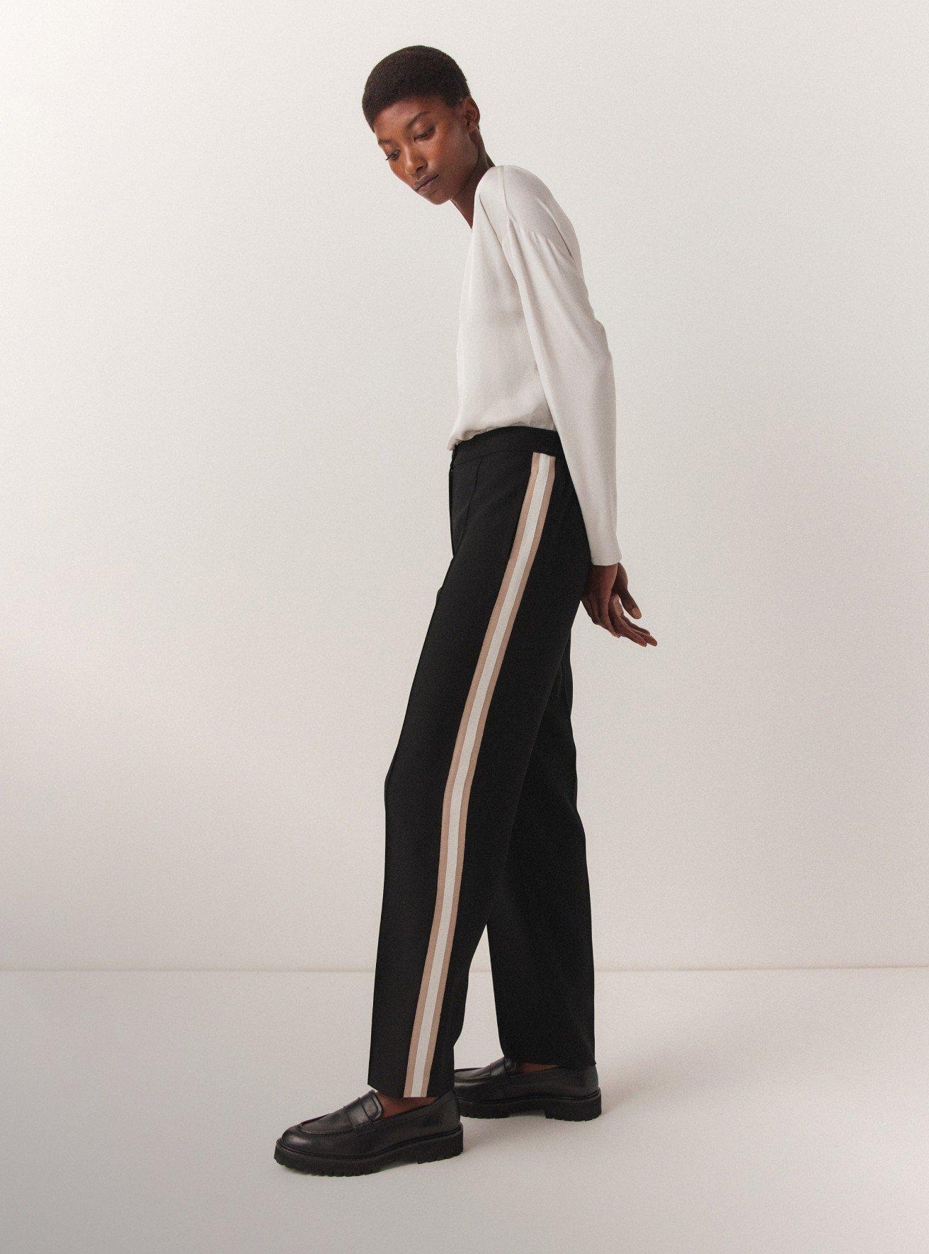 a man in white shirt and black pants standing in a white room