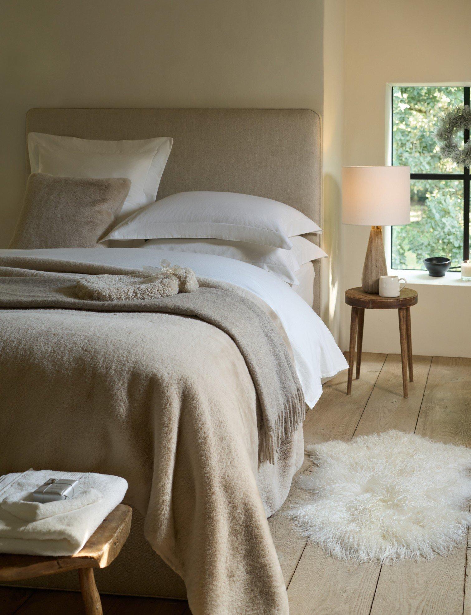 a bedroom with a bed, a window, a rug and a lamp