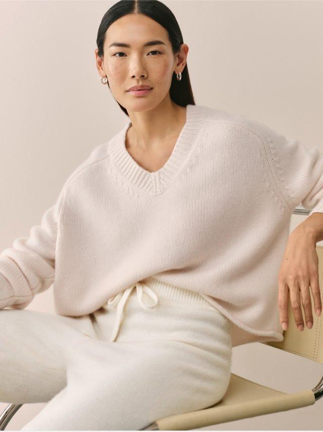 a woman in a white sweater sitting on a chair
