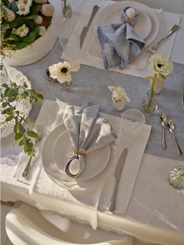 a table set for a meal with a white cloth and silverware