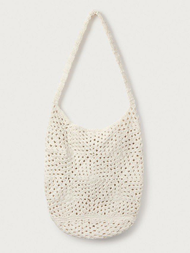 a white crocheted bag hanging on a wall