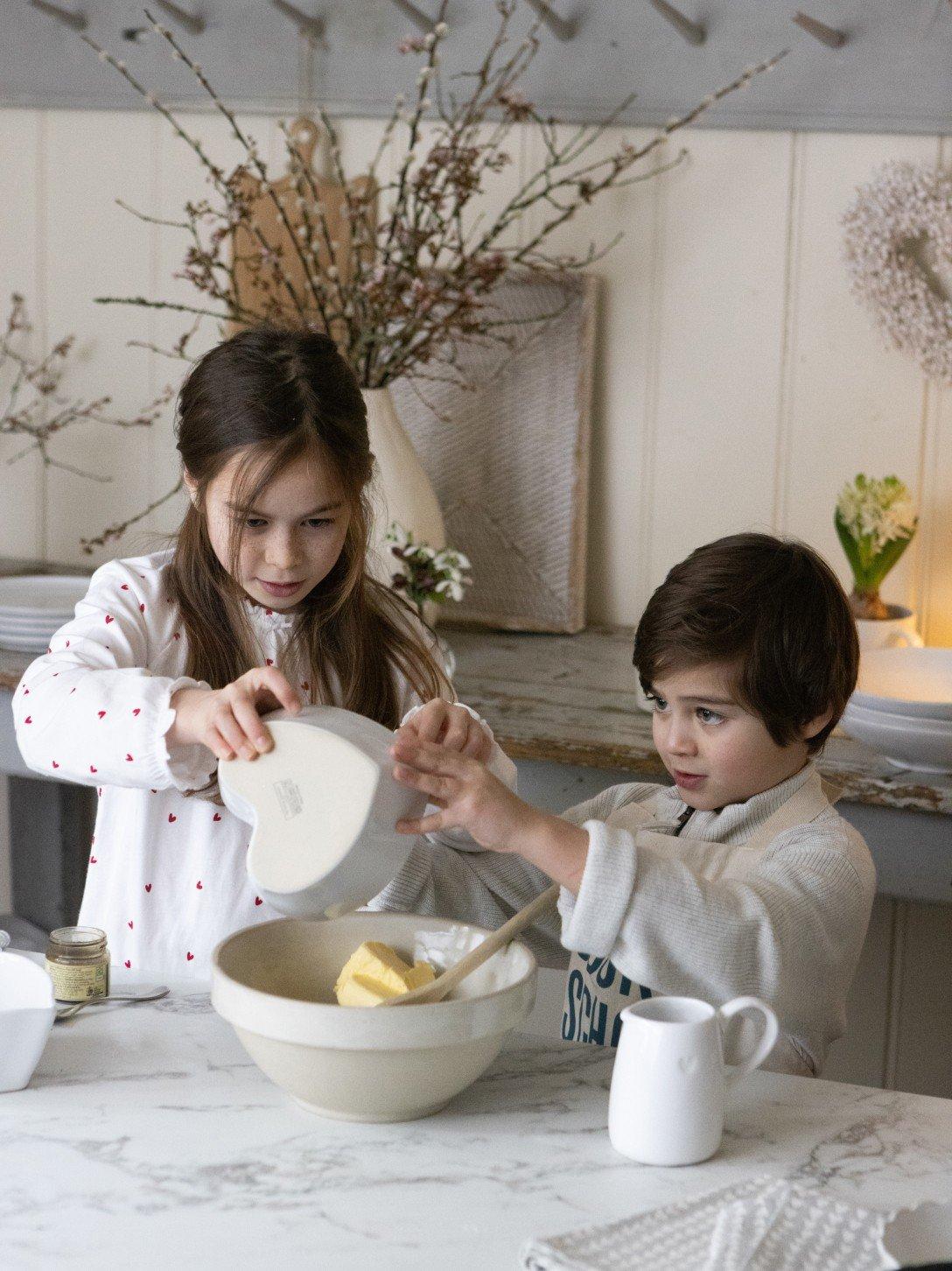three young girls are preparing a meal in a kitchen