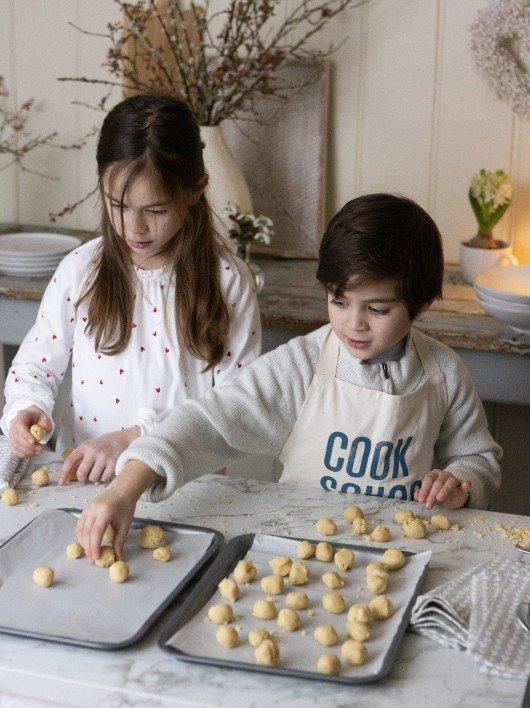 two children are making a chocolate cake on a table
