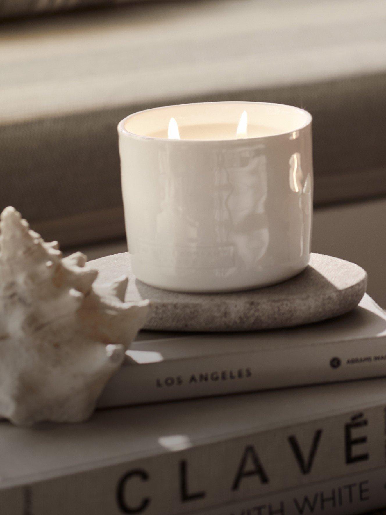 a candle sitting on top of a stack of books and a seashell