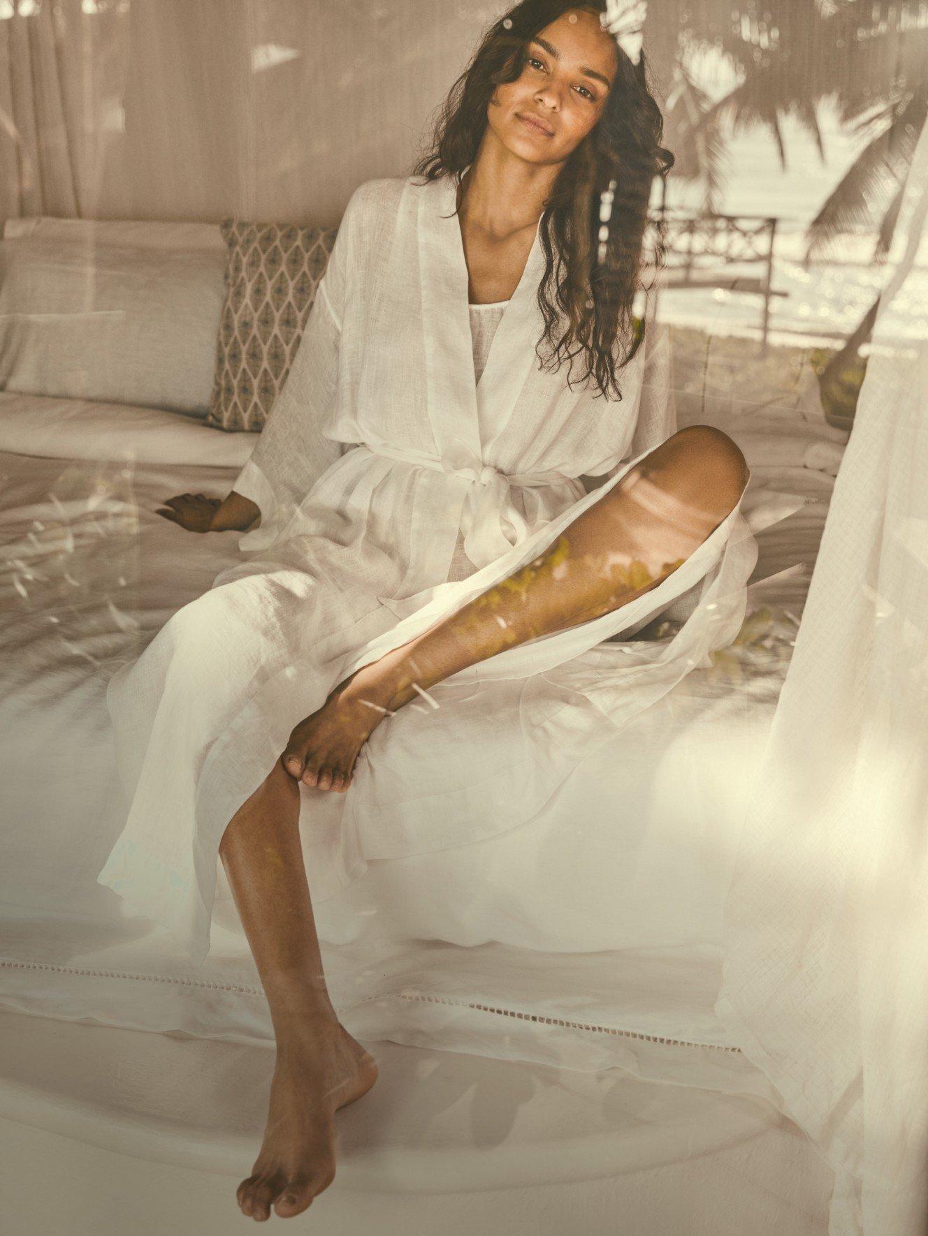 a woman in a white robe sitting on a bed