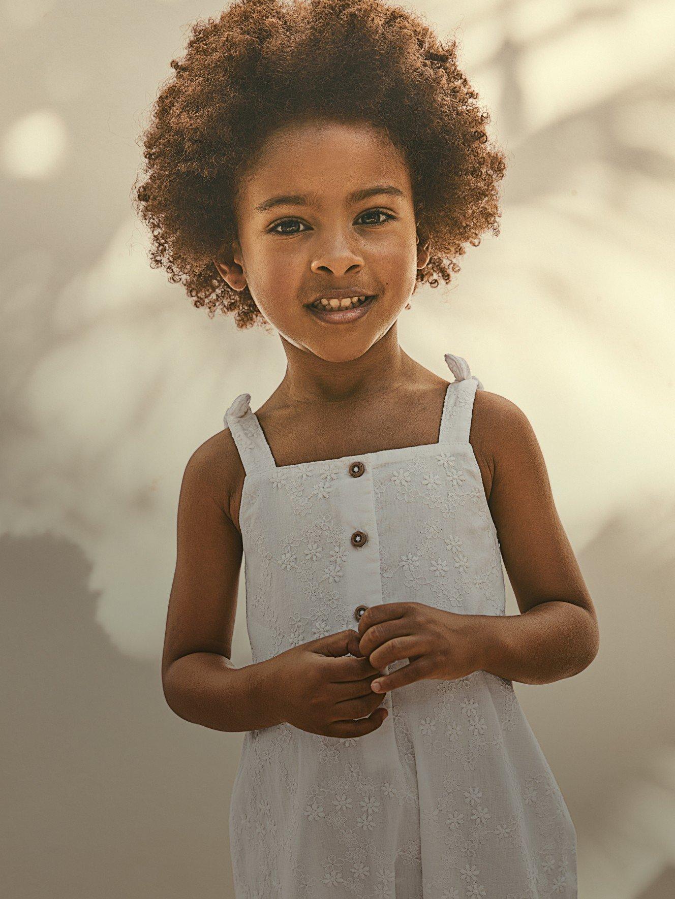 a young girl with a smile and a white dress