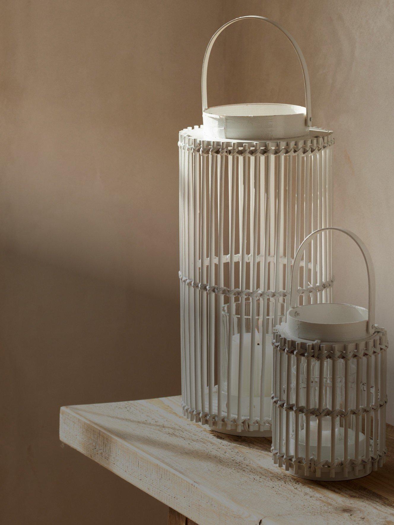 two white lanterns sit on a wooden table next to each other