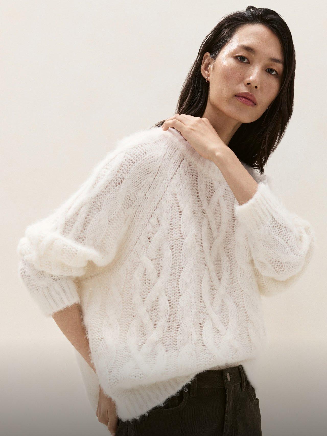 a woman in a white sweater posing for a picture