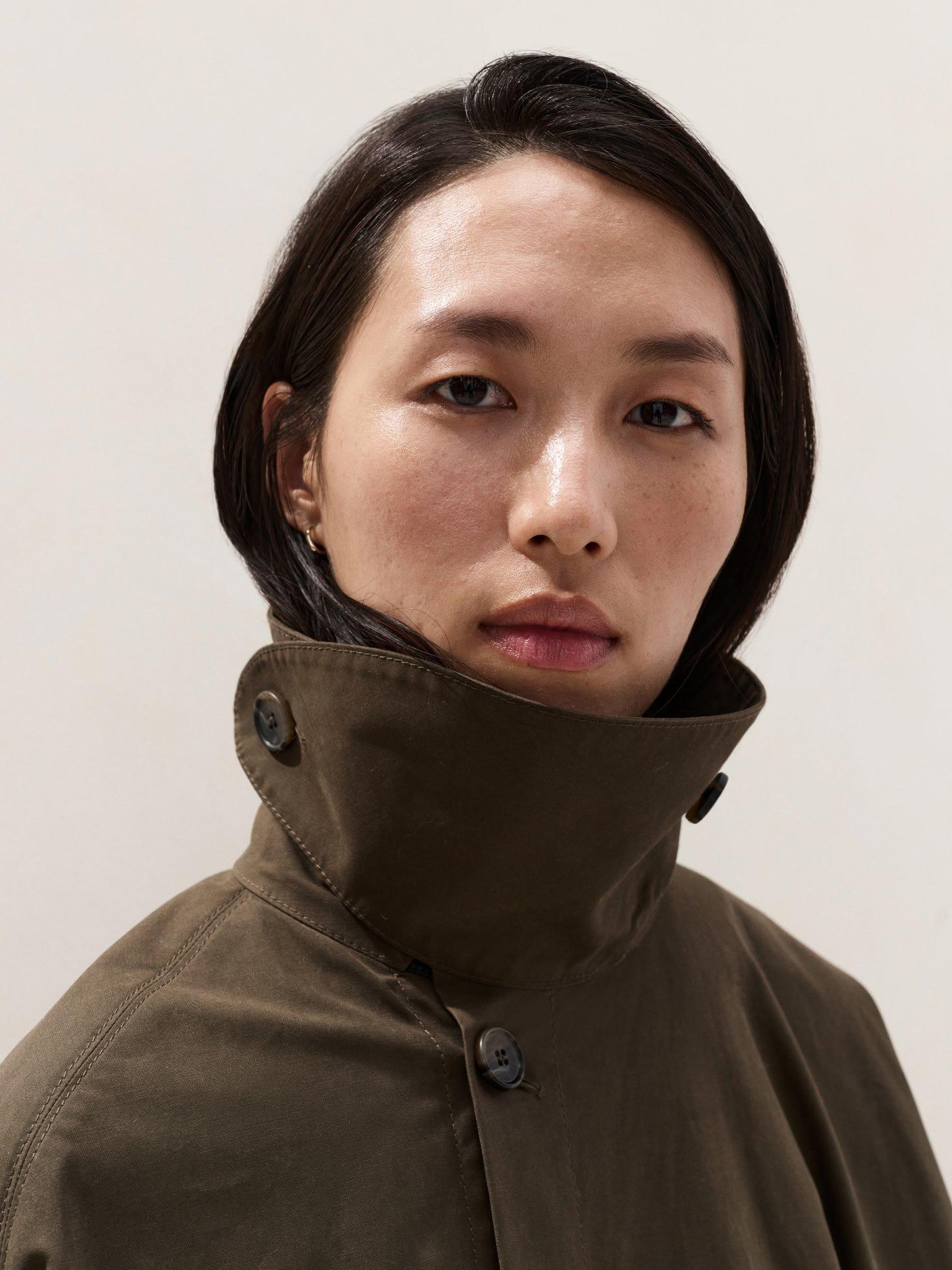 a woman with a jacket on and a white background