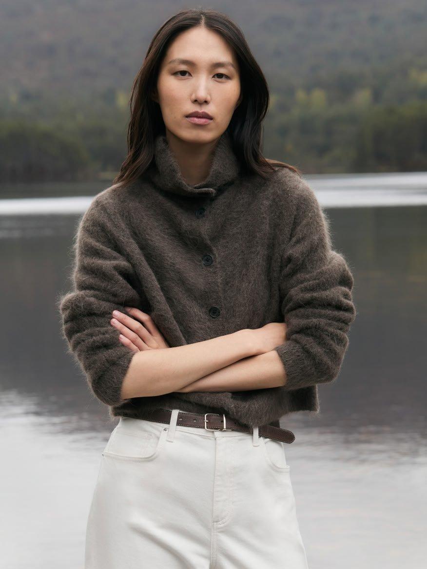 a woman standing in front of a body of water with her arms crossed