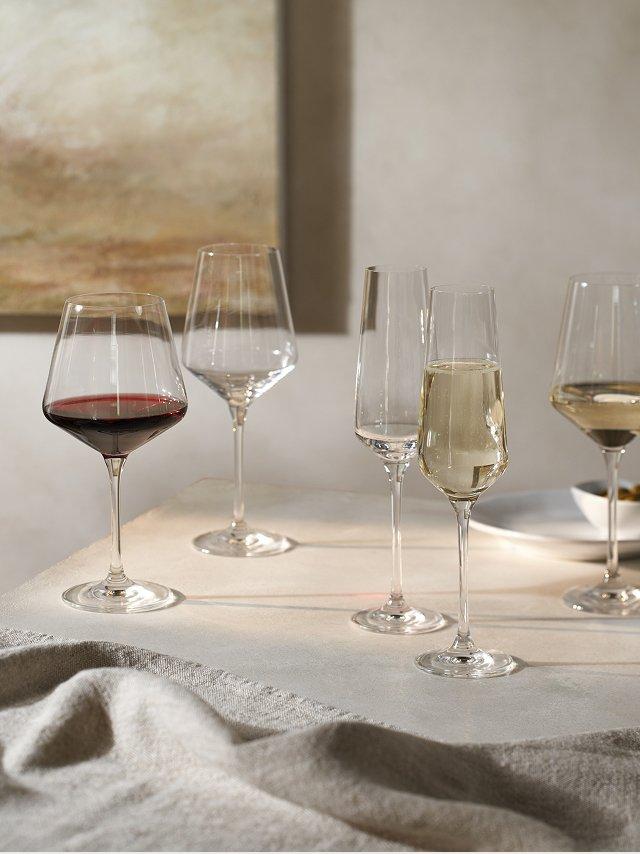a table with several wine glasses on it with a plate of food