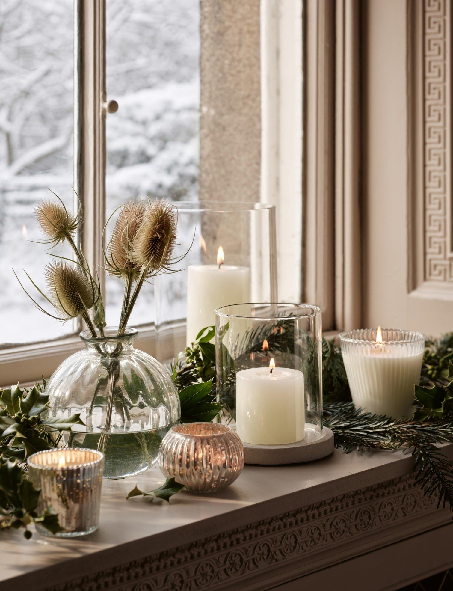 a window sill with candles and plants on it