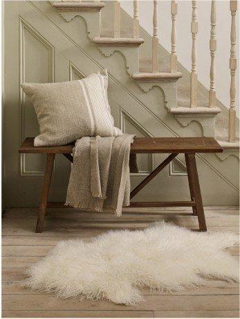 an indoor bench with a cushion and a blanket on it