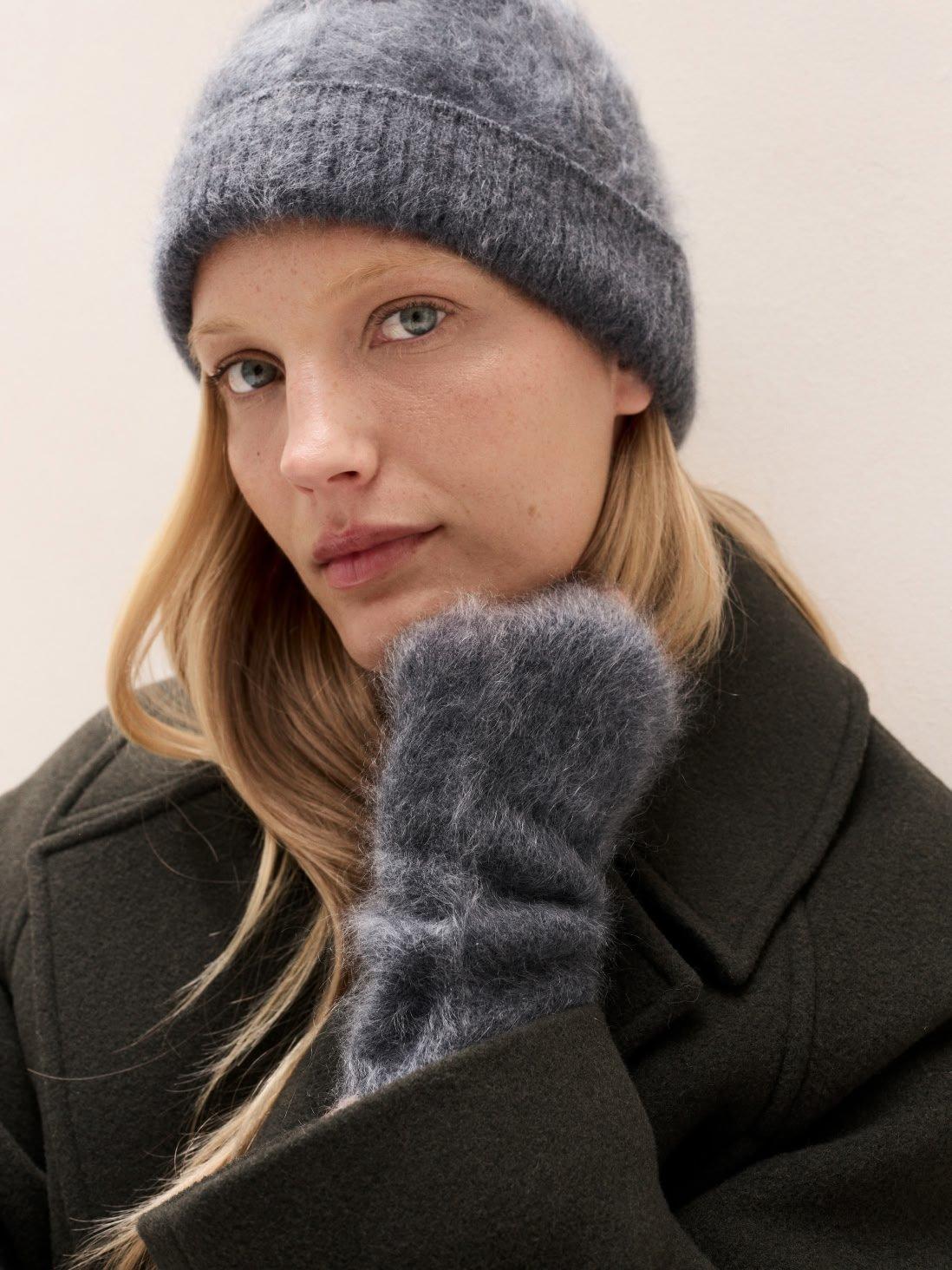 a woman with a hat and gloves on holding a phone