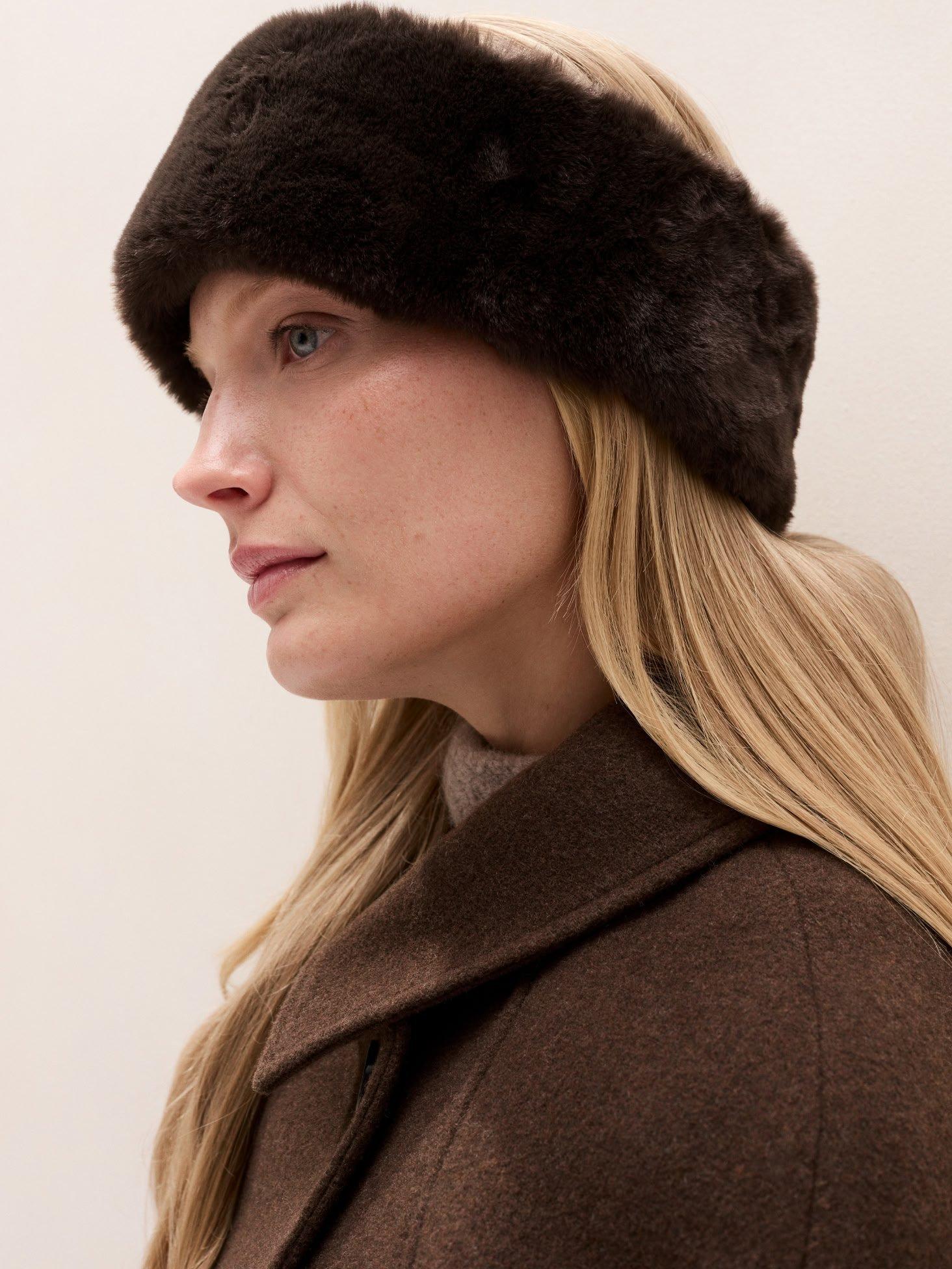 a woman with a fur headband on her head looking at something