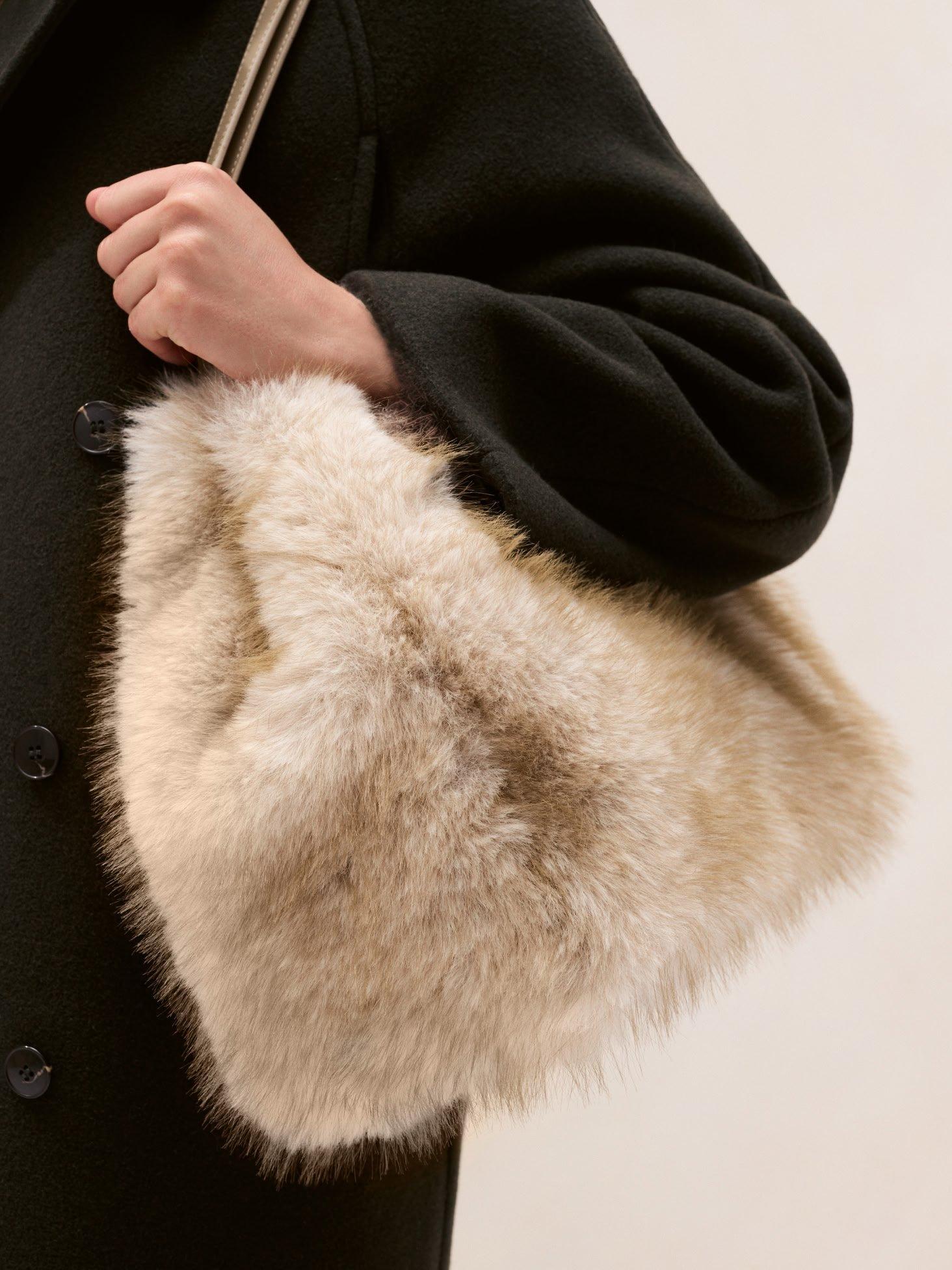 a woman holding a fur lined bag in her hand