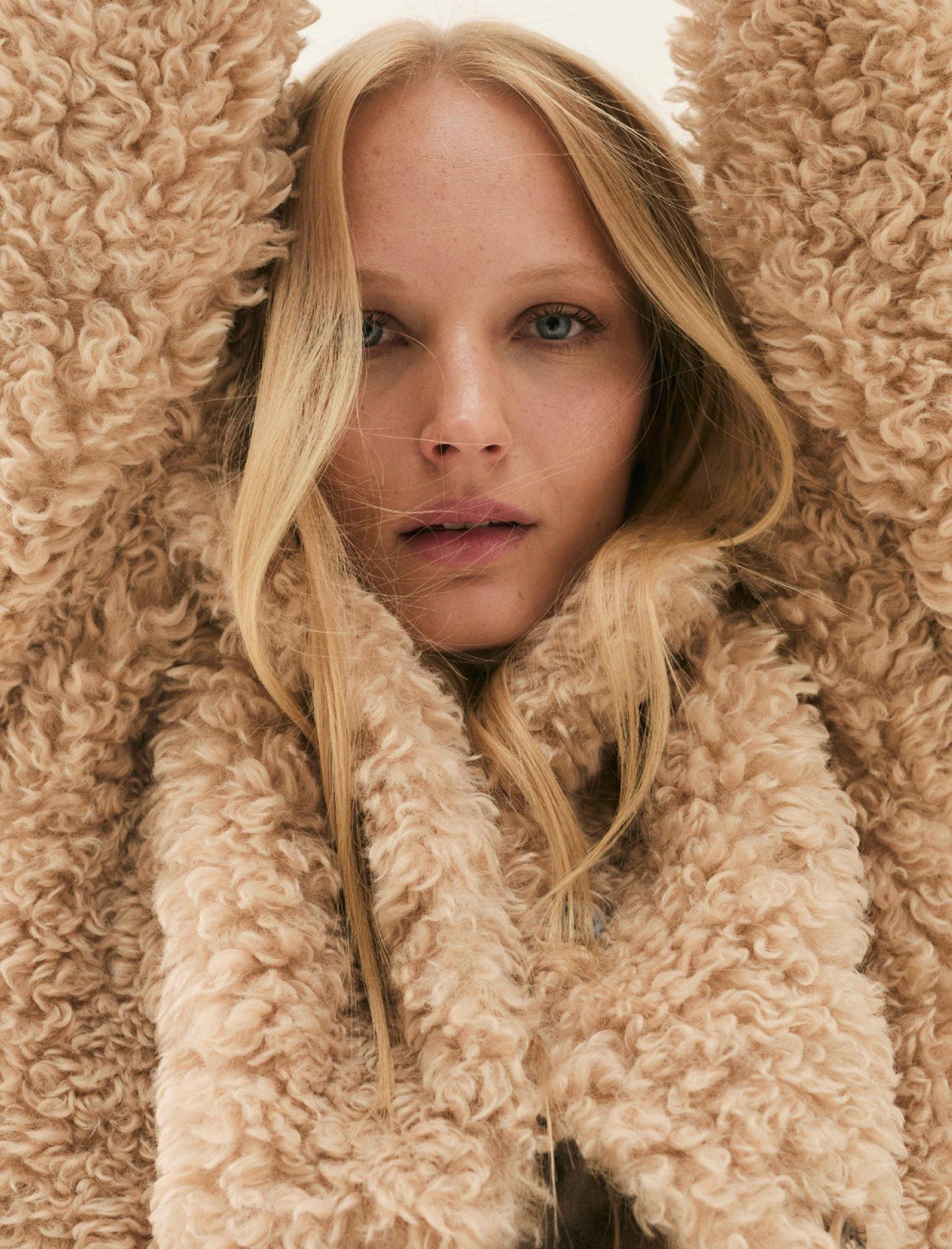 a woman with long blonde hair wearing a fluffy jacket