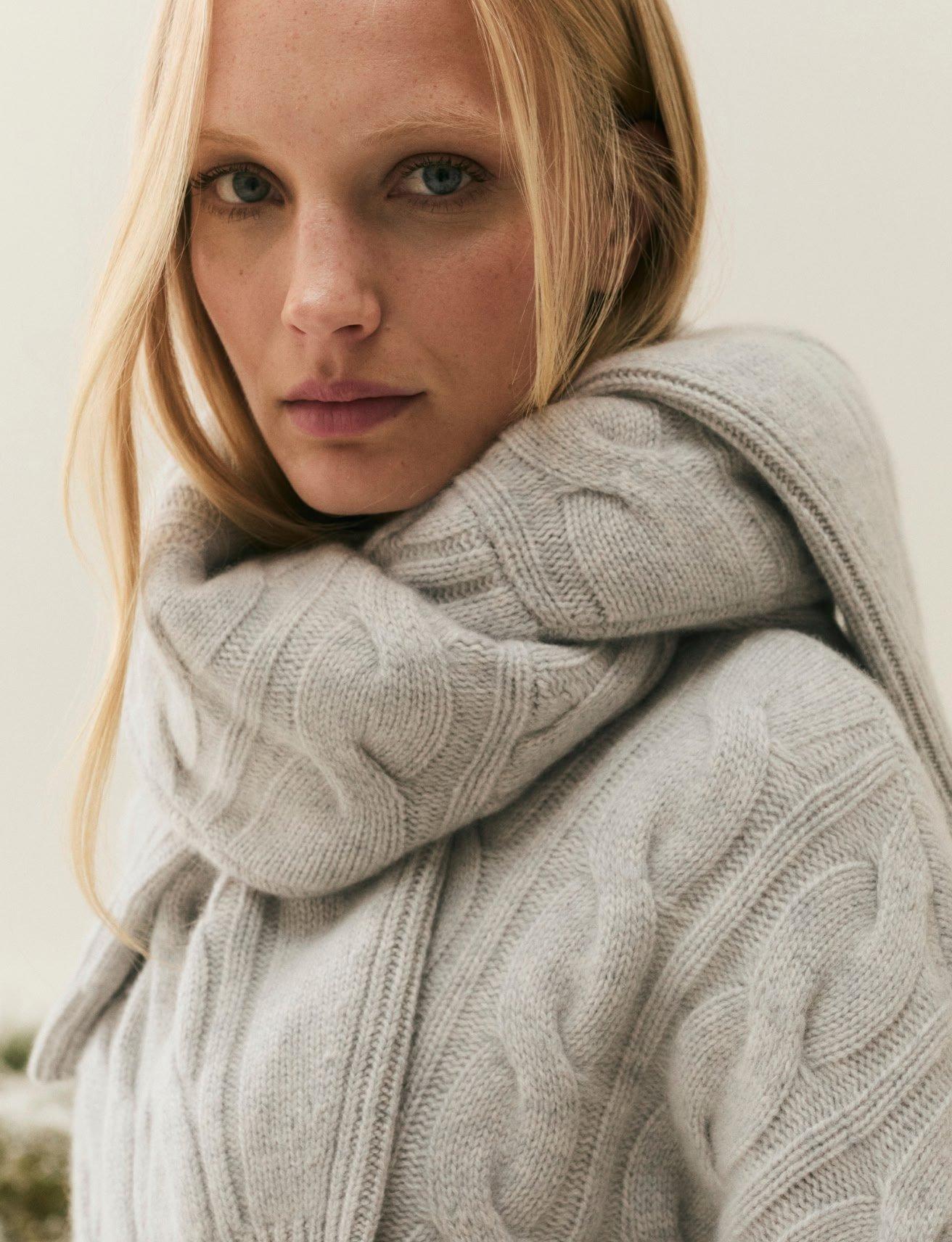 a woman in a grey sweater with a cell phone in her hand