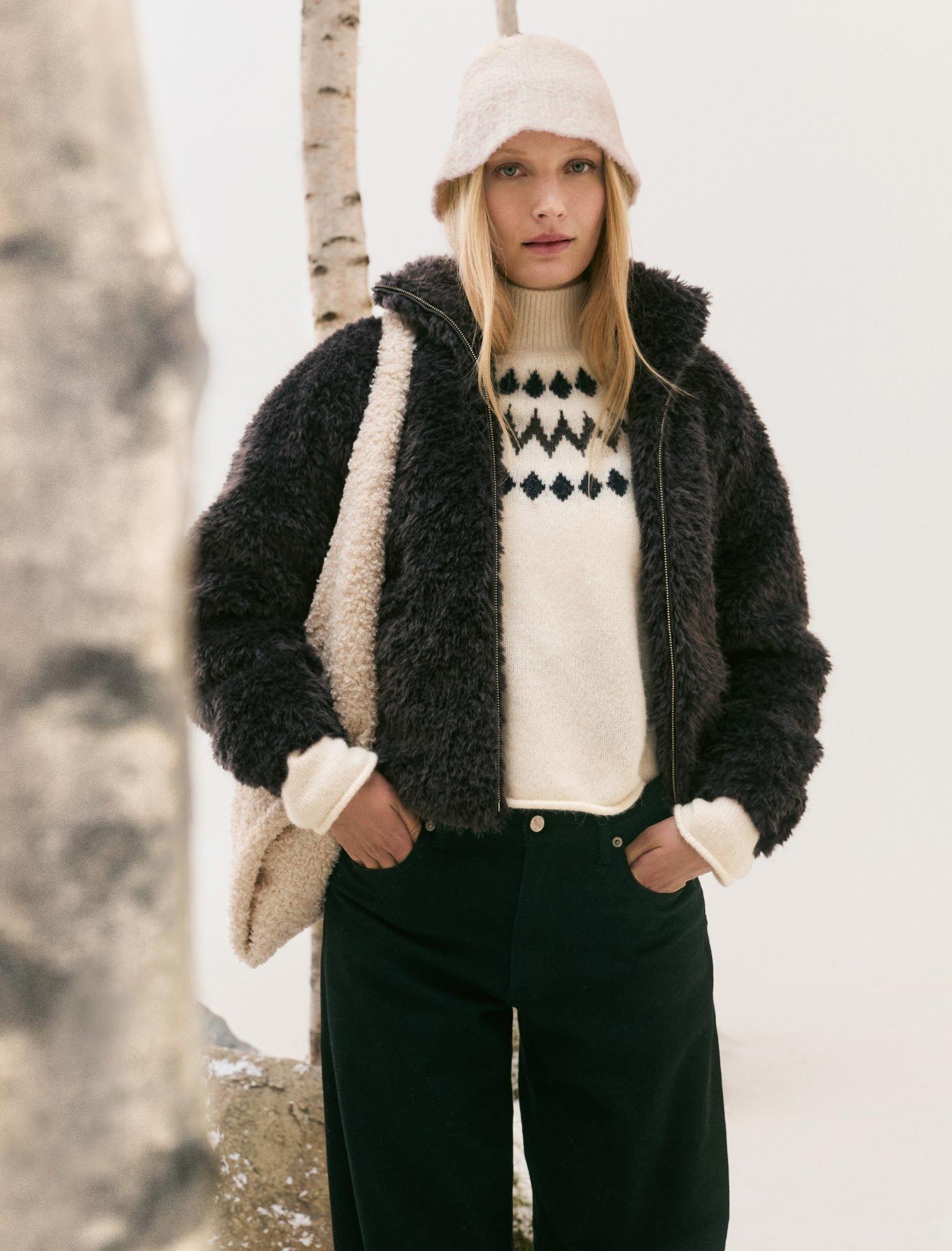 a woman in a black and white sweater and a furry jacket