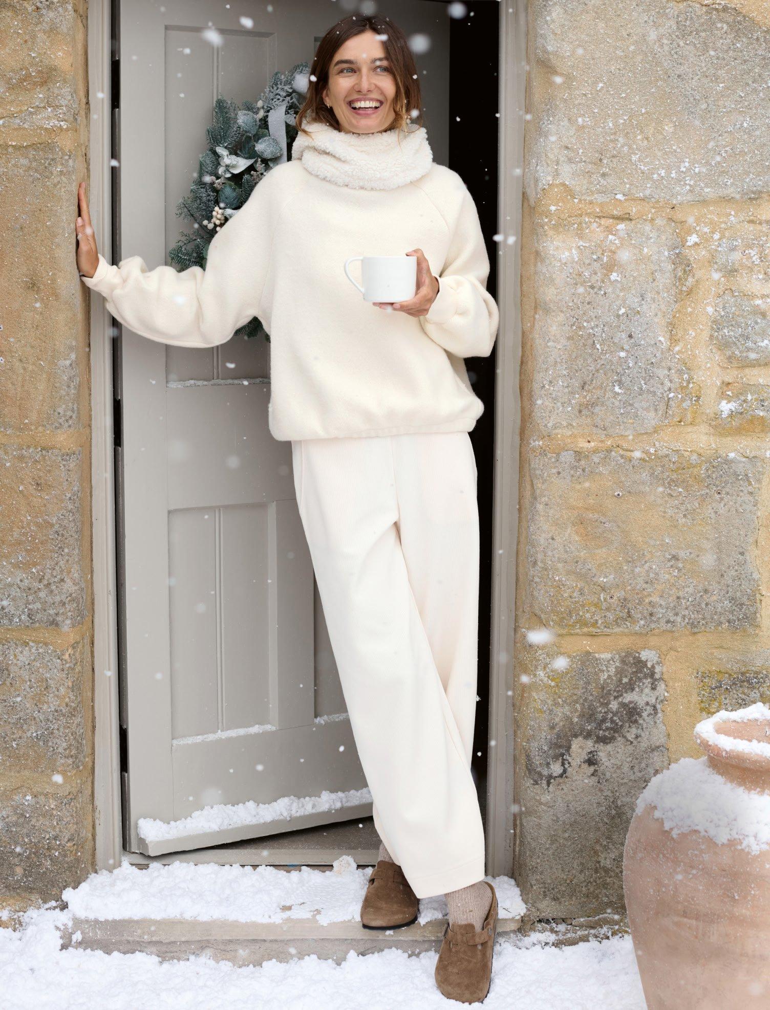 a woman in a white outfit standing in front of a door