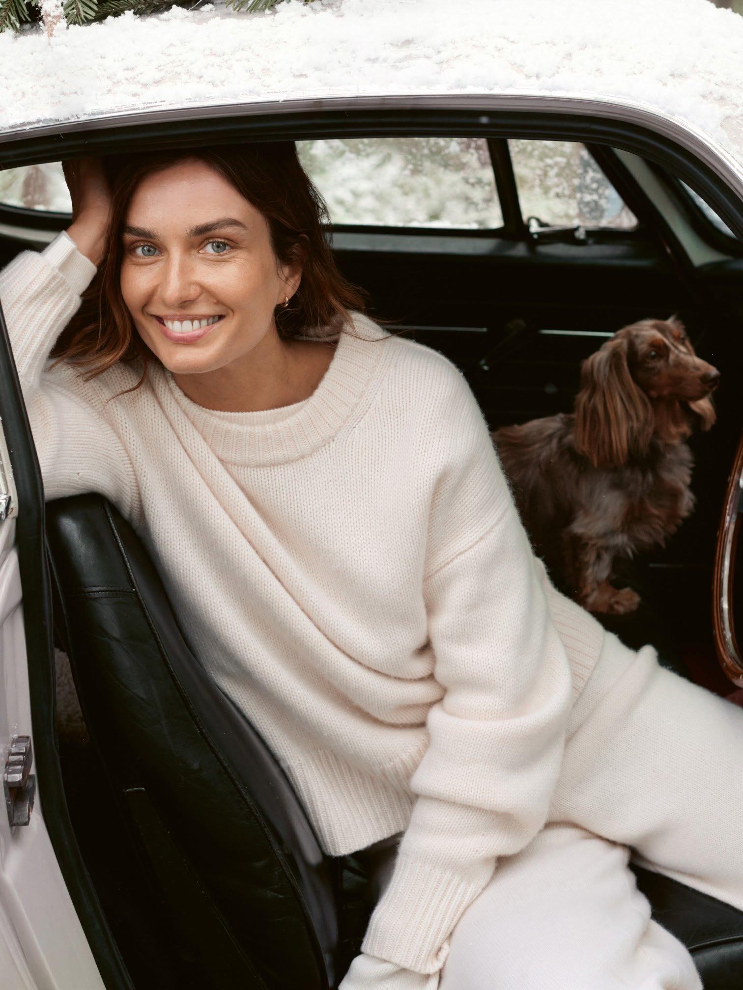 a woman sitting in the back seat of a car with a dog