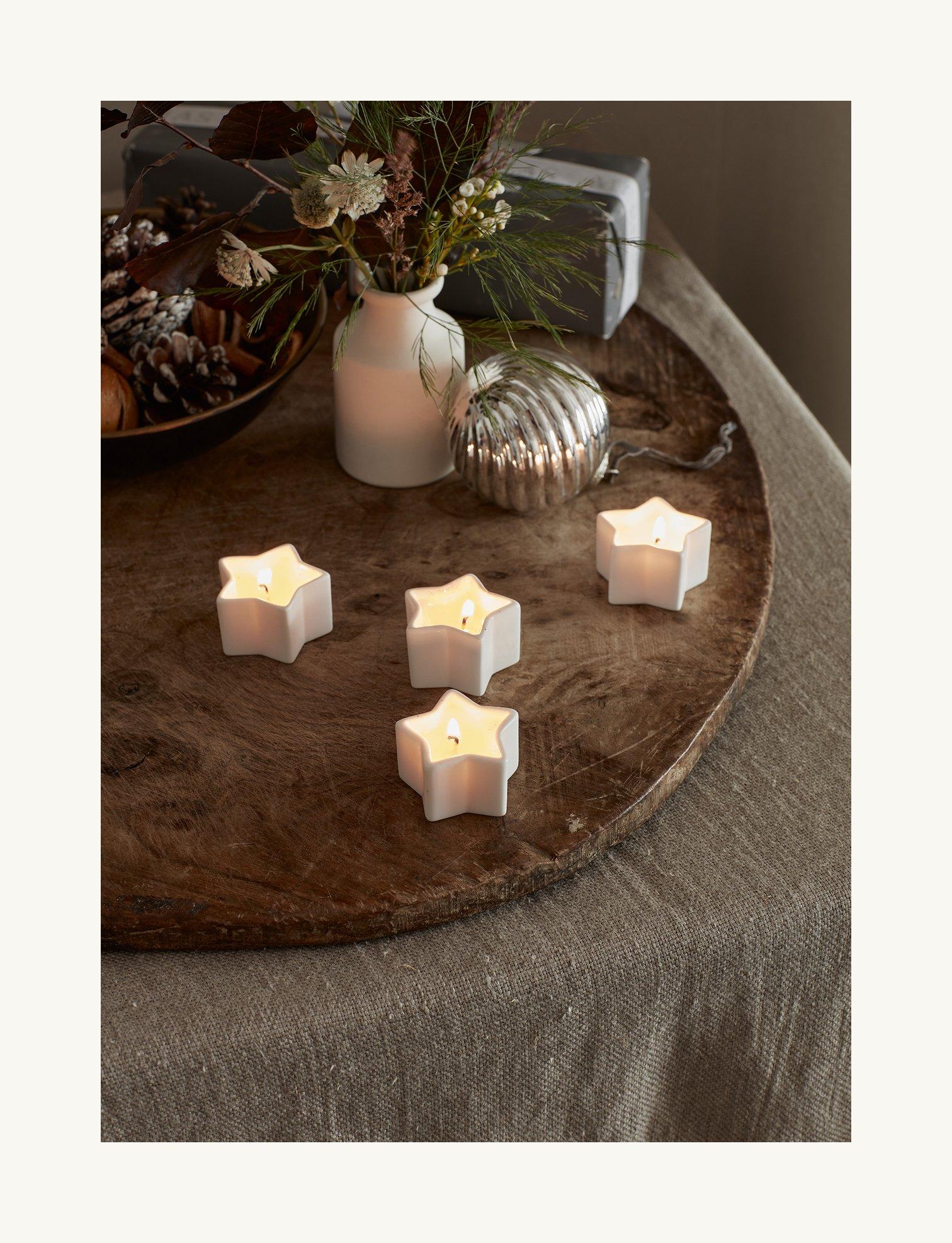 a wooden table with four small white candles on it