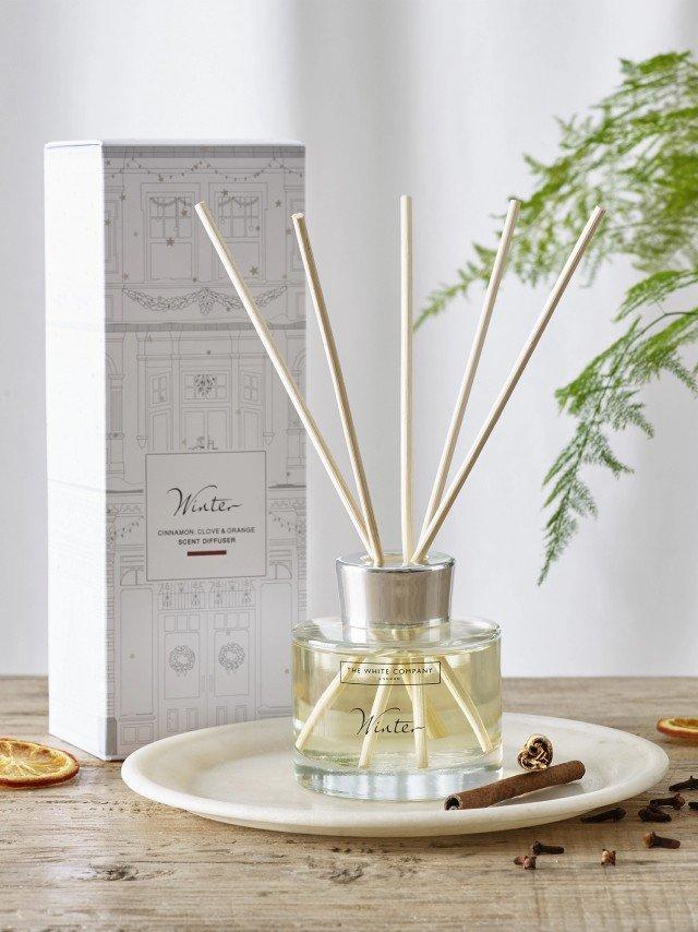 a reed diffuser sits on a plate next to a box of spices