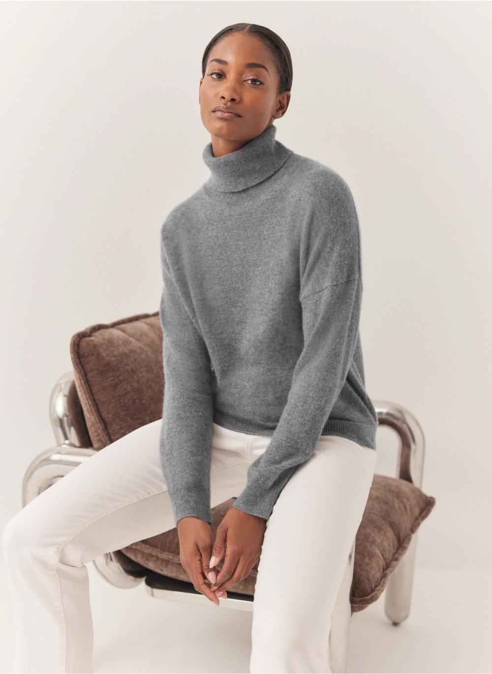 a woman in a turtle neck sweater sitting on a chair