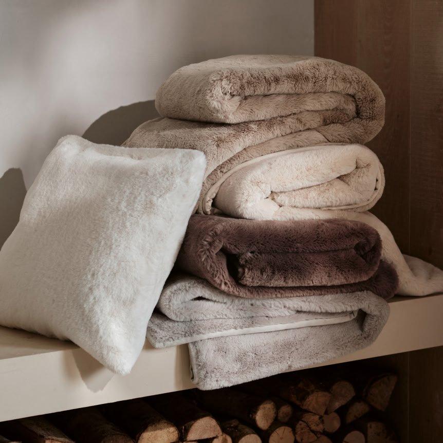 a stack of towels and pillows on a shelf next to logs