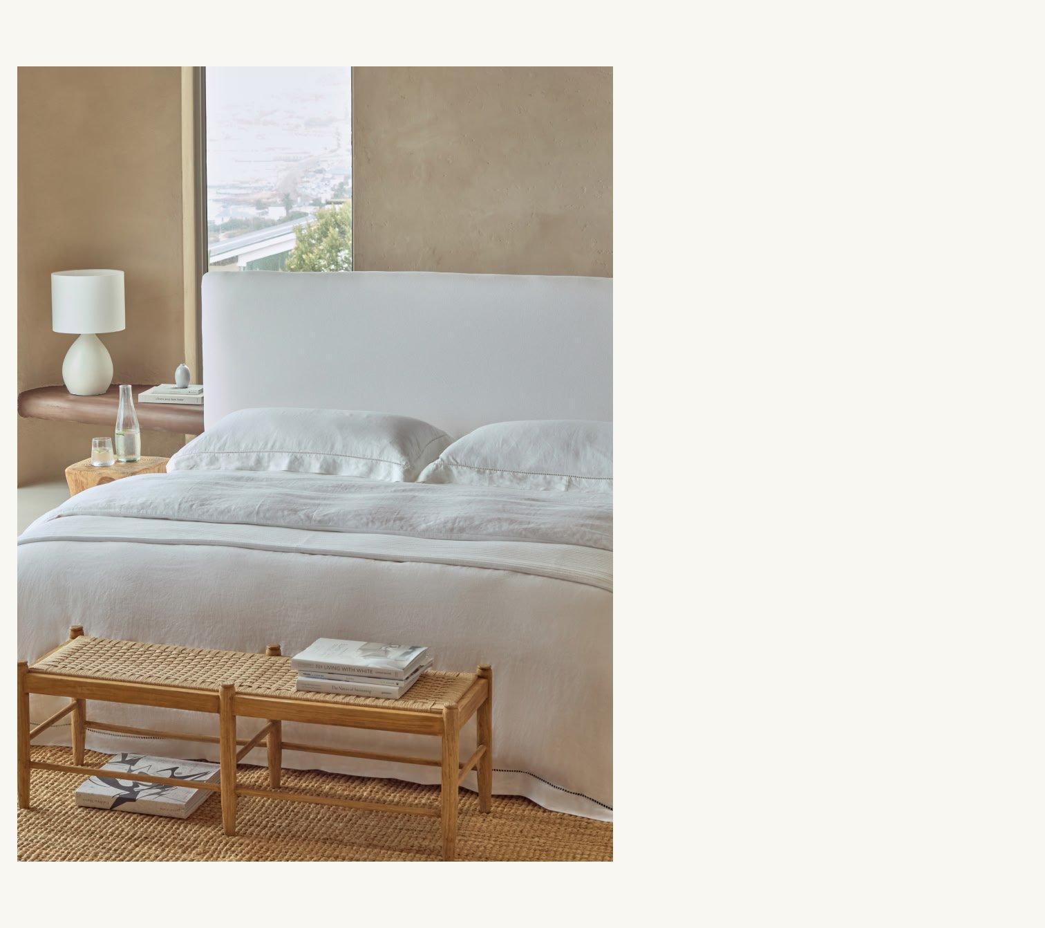 a bed with white sheets and pillows in a bedroom