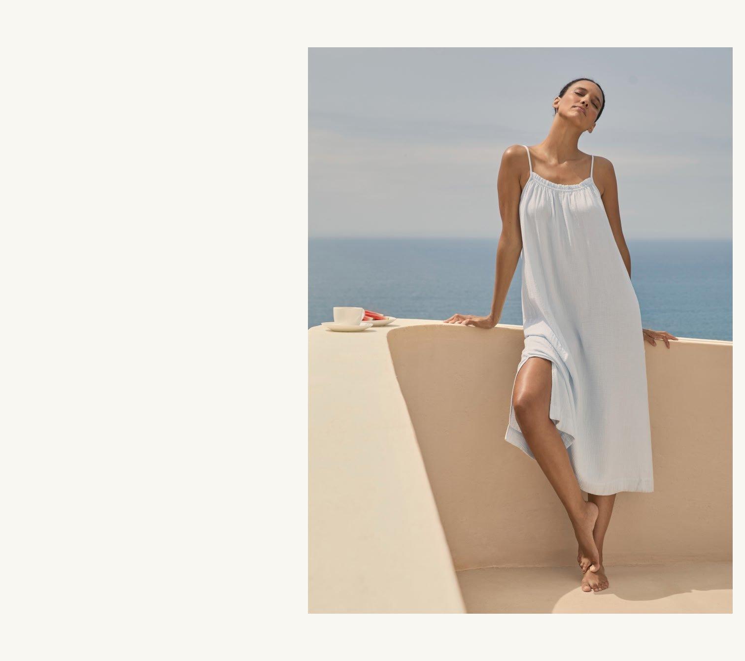 a woman in a white dress is standing on a ledge