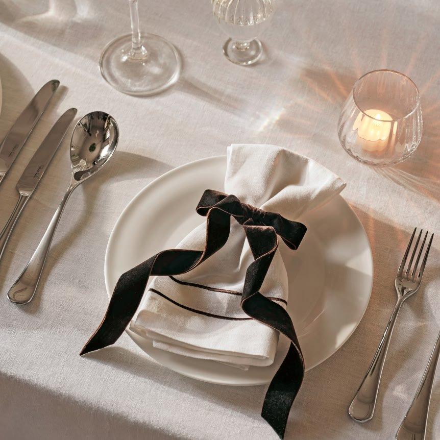 a white plate with a black bow on it next to silverware