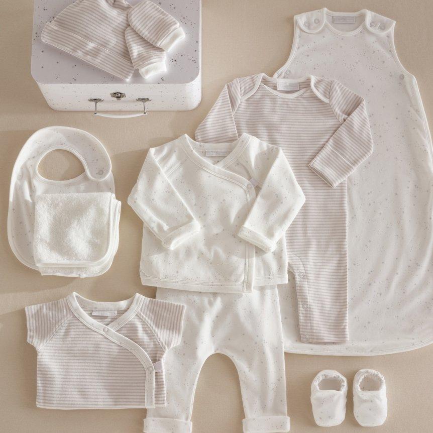 a baby's clothes are laid out on a table next to a suitcase