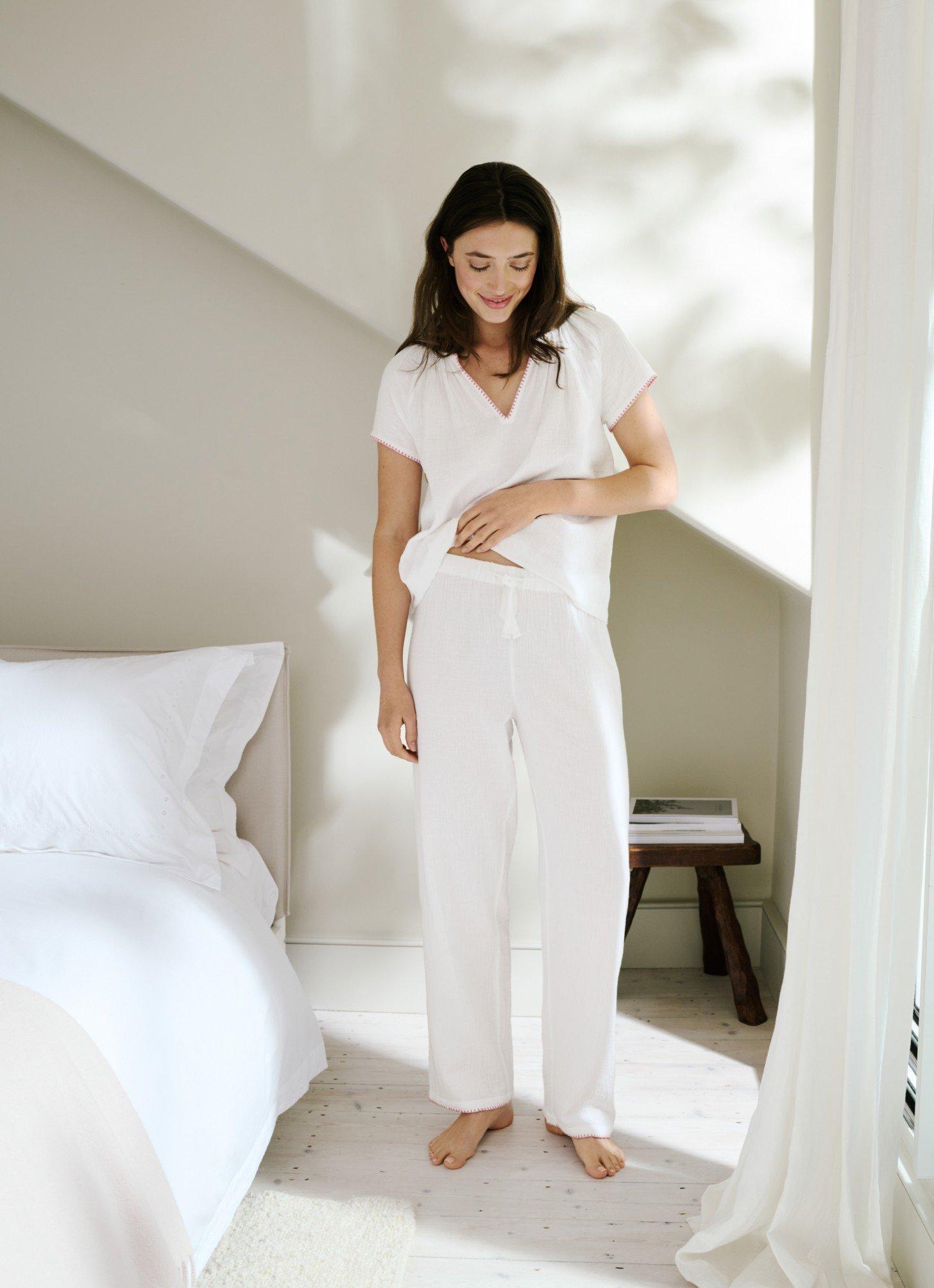 a woman in white pajamas standing in a bedroom