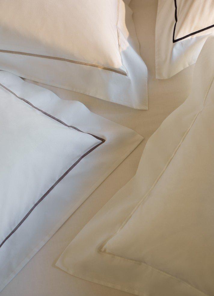 a close up of a bed with pillows and a sheet