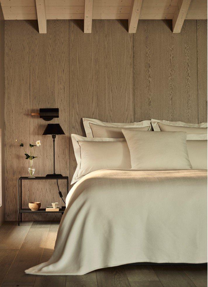 a bed with white sheets and pillows in a bedroom