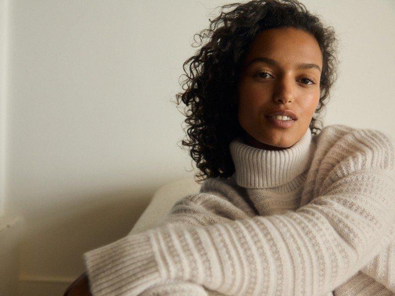 a woman in a white sweater sitting on a couch