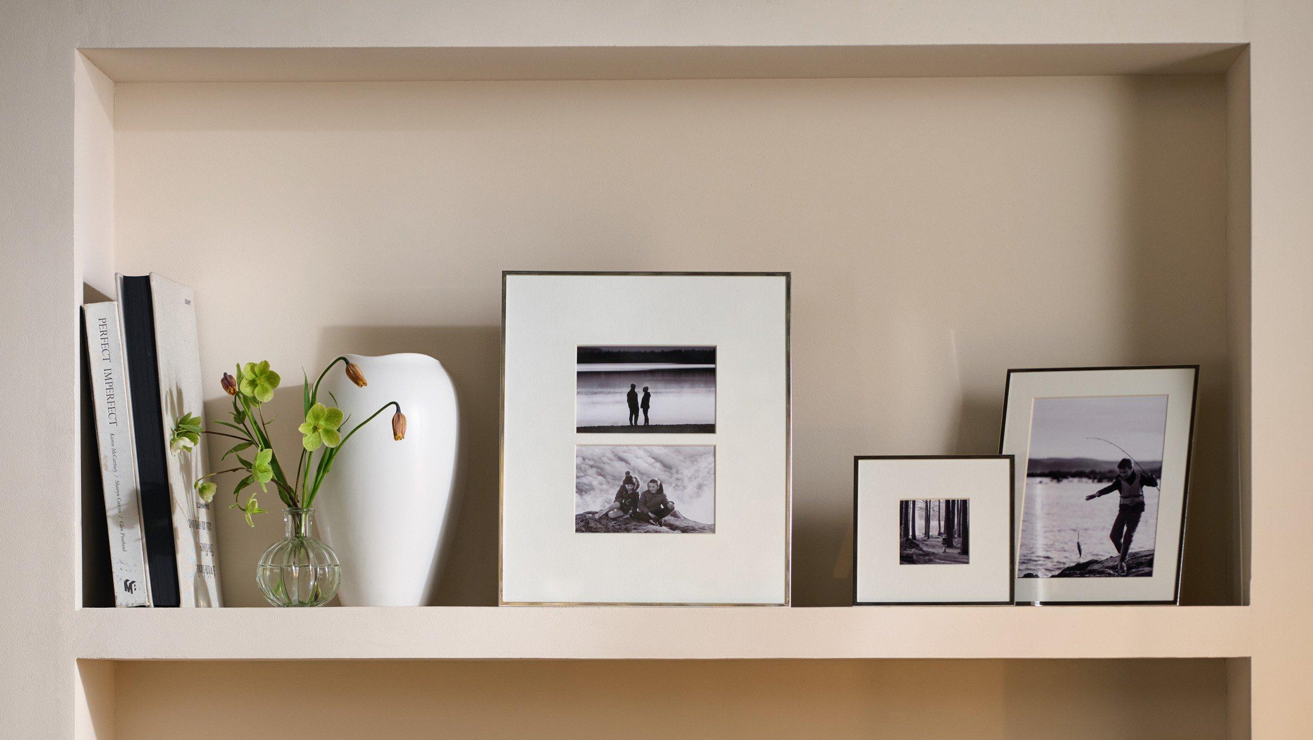 a shelf with a vase and some pictures on it