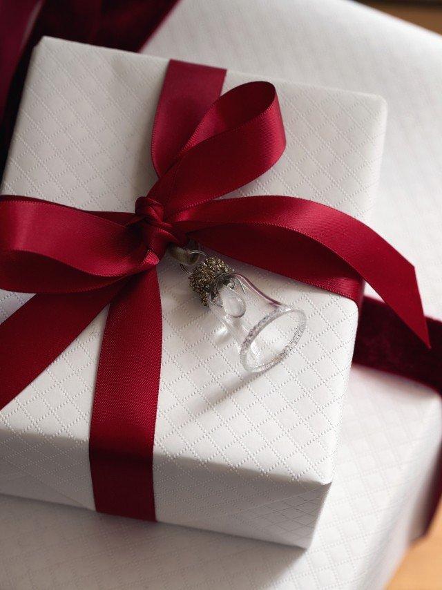a wrapped gift with a red ribbon and a bell on top