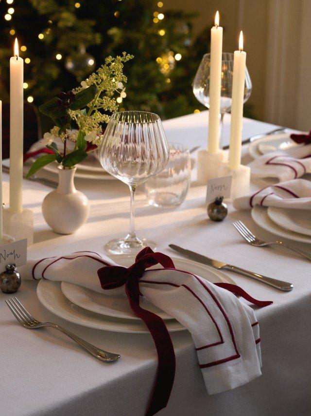 a table set for a christmas dinner with candles and wine