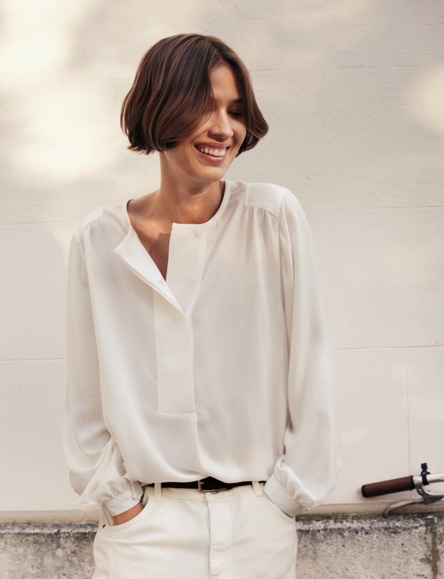 a woman in white pants and a white shirt standing next to a bike