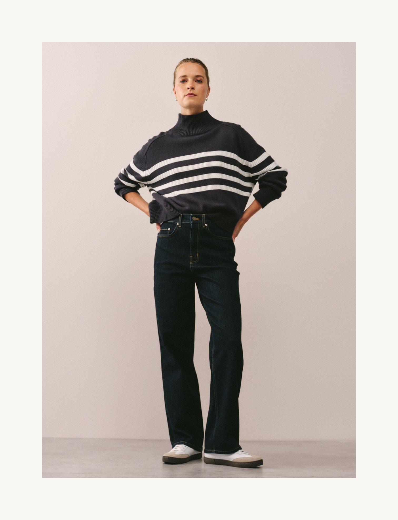 a woman in a striped sweater and jeans standing