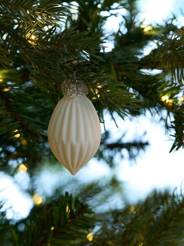 a white ornament hanging from a christmas tree branch