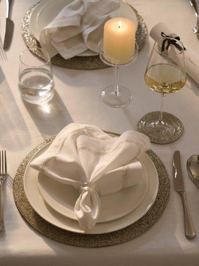 a table setting with a plate, napkin, silverware and candle