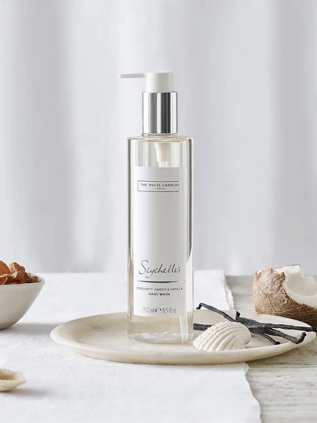 a bottle of body wash sitting on a plate next to a bowl of shells