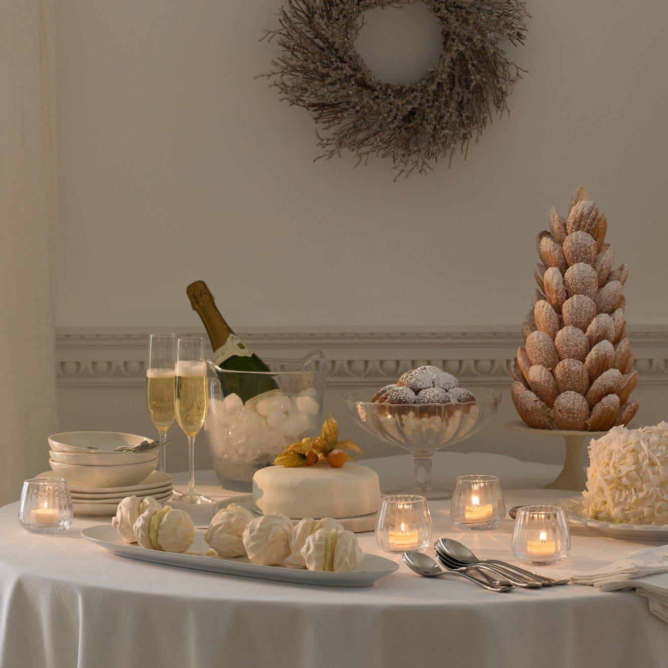 a table with a cake, wine, candles and a wreath