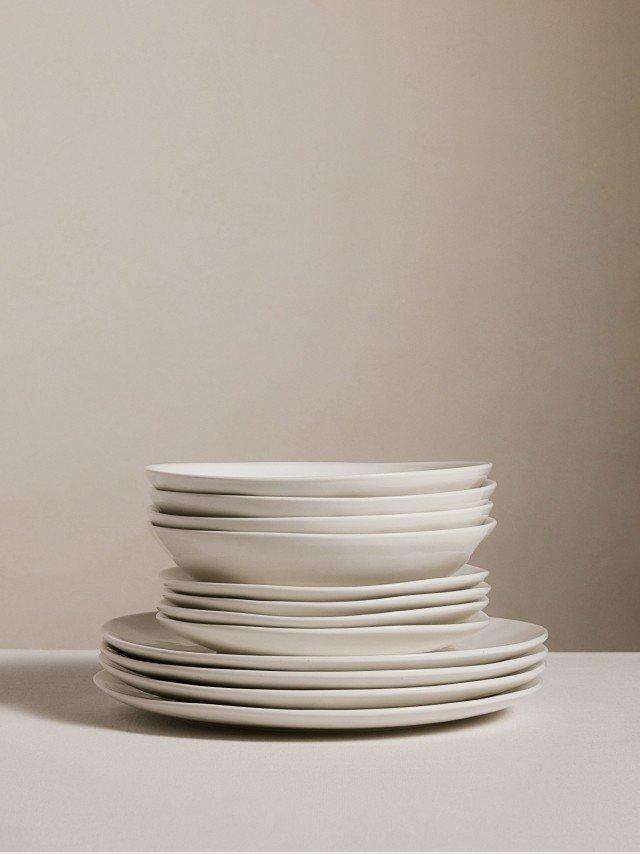 a stack of white plates on a table against a white background