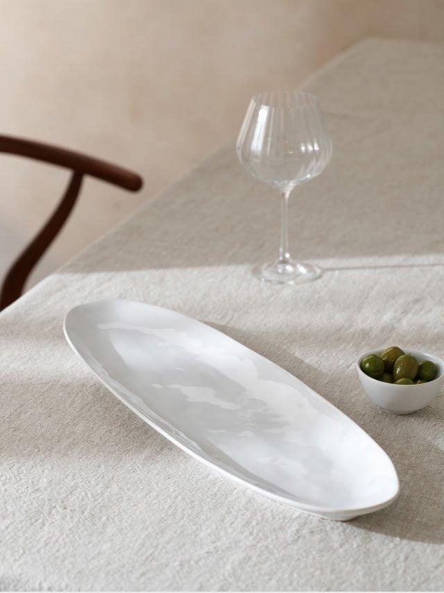 a white plate with a bowl of olives and a glass of wine